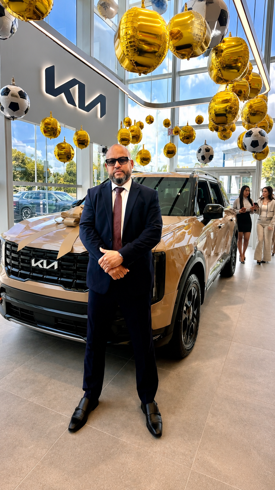 Alexander Montalvo standing beside a new Kia SUV in a Miami showroom