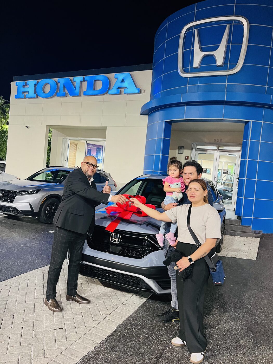 Familia recibiendo las llaves de su SUV nueva con lazo rojo