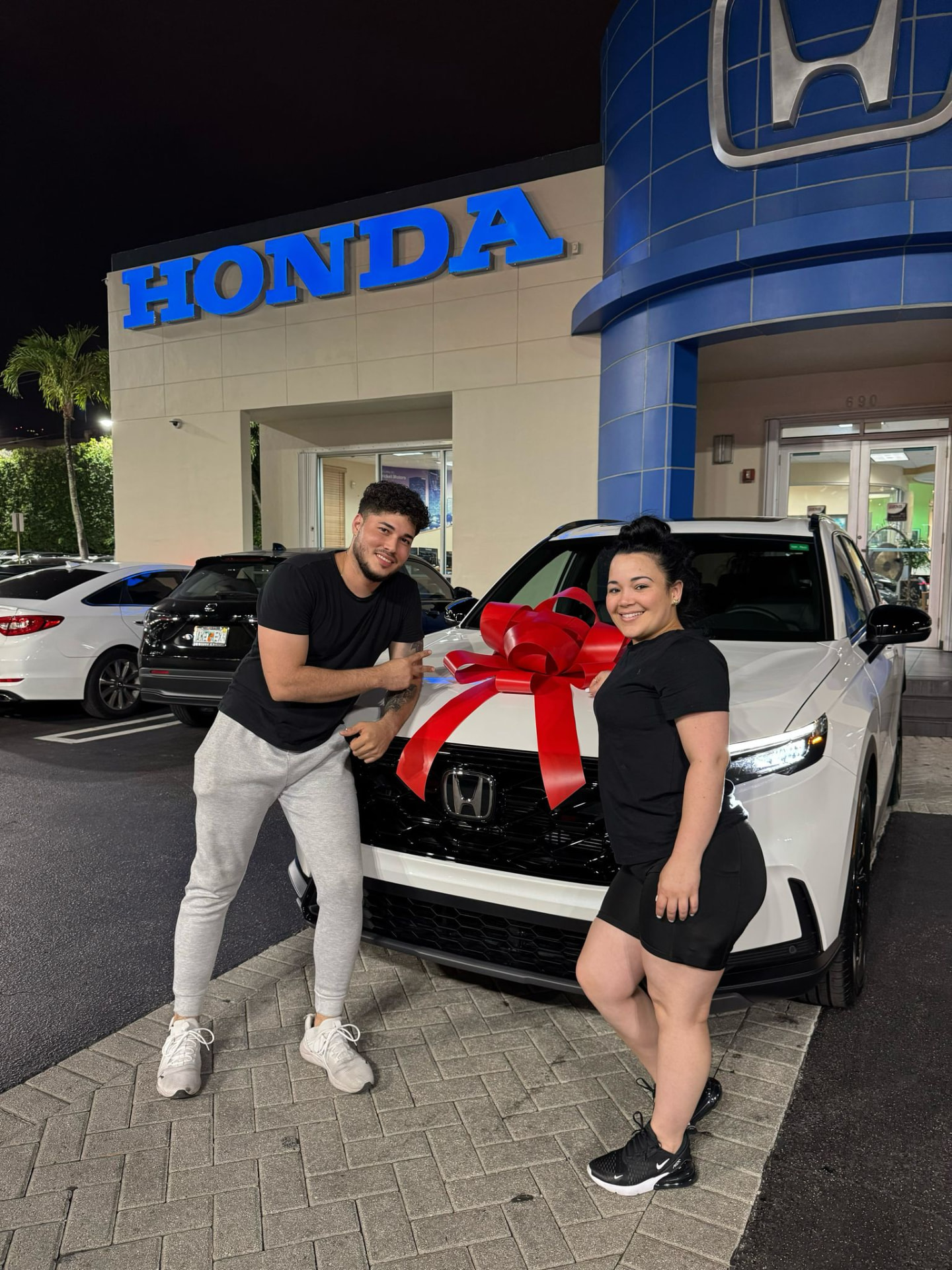 Pareja junto a su SUV nueva con lazo rojo de entrega