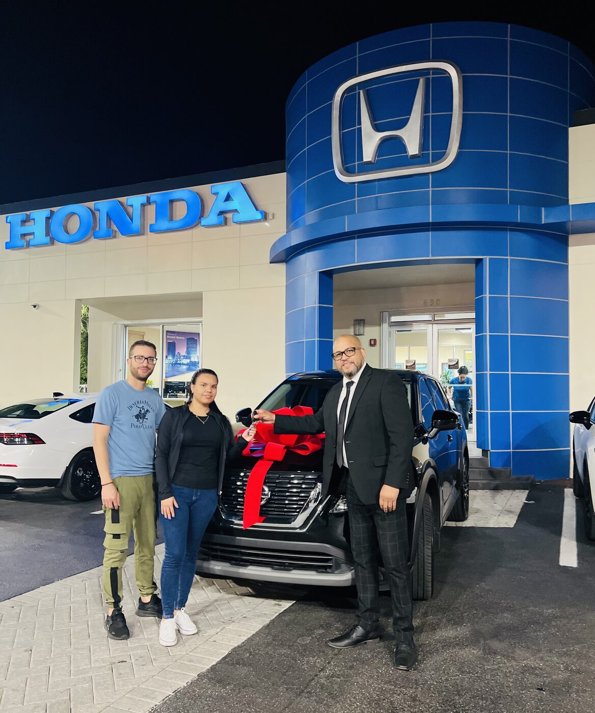 Pareja recibiendo las llaves de su SUV nueva con lazo rojo